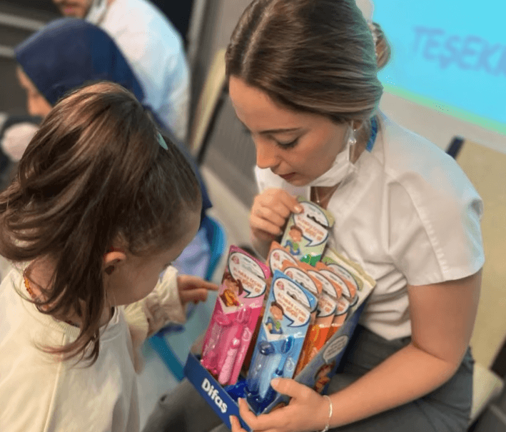 Ein Zahnarzt zeigt einem jungen Mädchen während einer Bildungsveranstaltung verschiedene Zahnbürsten